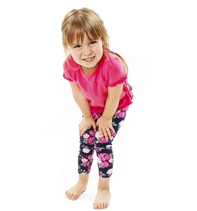 Little girl taking a stool retentive posture, leading to constipation and slow bowel movements