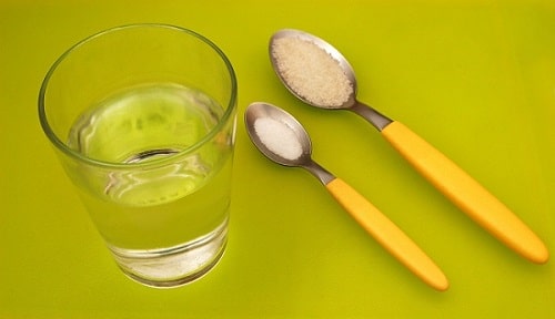 Electrolytes in a spoon next to a glass of water